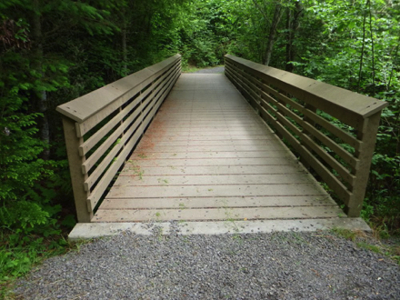 Foot bridge with a transition from compacted gravel to hard surface of composite boards